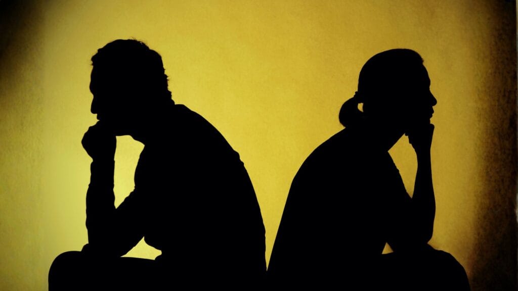 sylwetki pary, kobiety i mężczyzny siedzących plecami do siebie